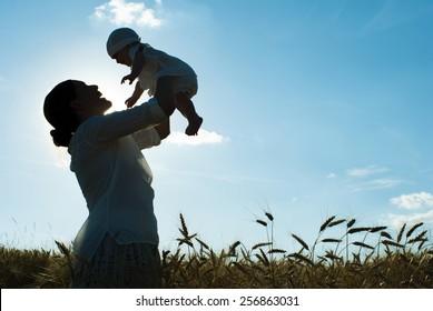 Mother Holding Her Baby On A Wheat Filed, Silhouette