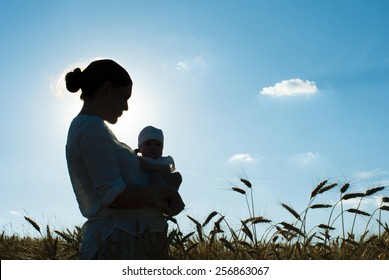 Mother Holding Her Baby On A Wheat Filed, Silhouette