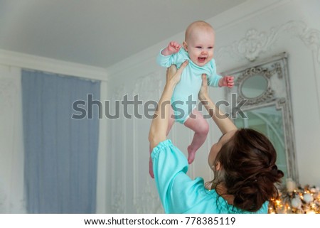 Mother holding her child. Young mother playing whith her daughter. Woman and new born girl relax at home. Mother breast feeding baby.