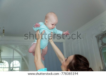 Mother holding her child. Young mother playing with her daughter. Woman and new born girl relax at home. Mother breast feeding baby.