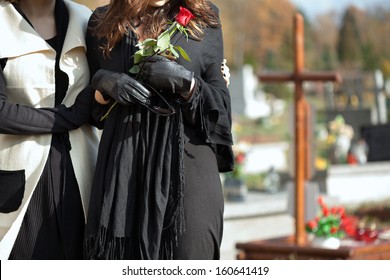 Mother holding her daughter standing above grave of family member