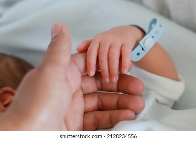 Mother Holding Her Newborn Baby Hand With Name Tag Armband At Hospital. Little Infant Boy First Day Of Life. Mom And Child Concept.