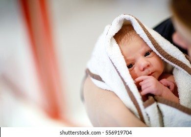 Mother holding her newborn baby daughter after birth on arms. Mum with baby girl, love. New born child cuddling in mama arms and looking at the camera. Bonding, family, new life