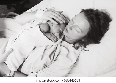 Mother Holding Her Newborn Baby Child After Labor In A Hospital. Mother Giving Birth To A Baby Boy. Black And White Photo.