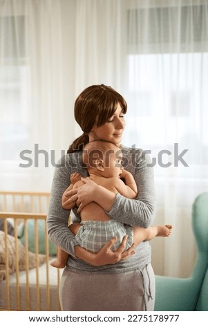 Mother holding her newborn baby boy and playing with him at home