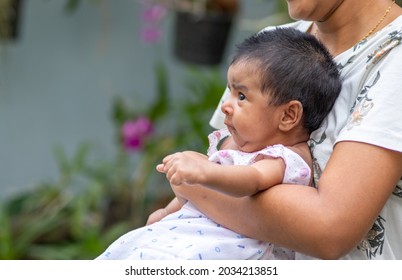 Mother Holding Her Precious Newborn Baby Girl In Her Arms, Expressions Of The Baby's Face Close Up Side View.