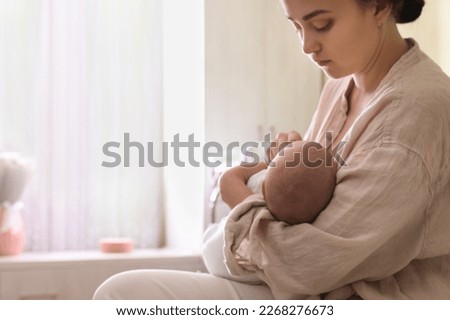 Mother holding her sleeping baby at home, closeup