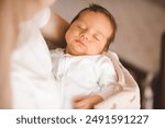 Mother holding infant baby boy 1-2 months old sleeping on hands in room. Motherhood.