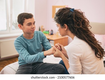 Mother Holding Kid For Hands And Having Serious Conversation But Boy Feels Uncomfortable. Sitting On Bed In Sleeping Room