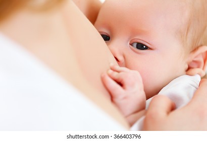  mother holding newborn baby in an embrace and breastfeeding