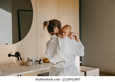 Mother holding newborn baby on shoulder, with a burping cloth.
