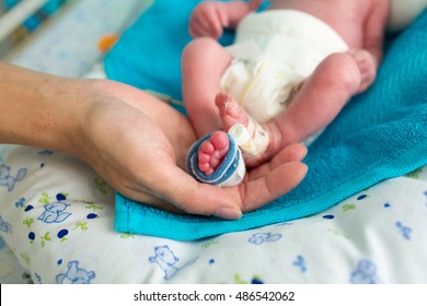 mother holding premature baby legs with neonatal infant pulse oximeter 