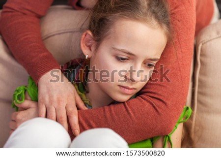 Mother holding sad teenager girl from behind trying to provide comfort and support in a dire situation - close up