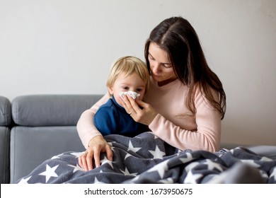 Mother Holding Sick Child, Lying Together On A Couch At Home With Fever, Running Nose And Temperature, Resting