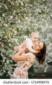 Mother Holding Small Baby Girl Next To The Blooming Tree, Spring Family Photosession