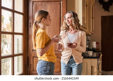 Mother holding smartphone and talking with serious face while her child drinking tea - Powered by Shutterstock