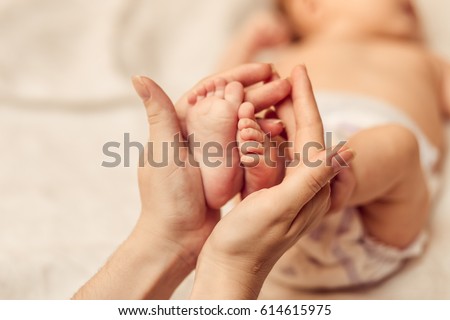 Mother holding tiny foot of newborn baby