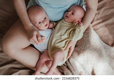 Mother Holding Two Twin Babies In Bed At Home