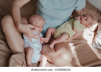 Mother Holding Two Twin Babies In Bed At Home