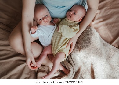 Mother Holding Two Twin Babies In Bed At Home