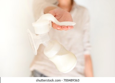 Mother holds breast pump in her hand, blurred background
