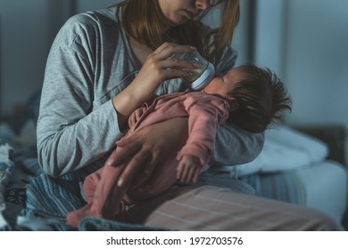 Mother Holds Her Two Moths Old Baby Taking Care Of Her At Home - Caucasian Woman With Her Newborn Child Bottle Feeding Milk On Lap At Night - Affectionate And Bonding Childhood And Motherhood Concept