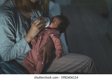 Mother Holds Her Two Moths Old Baby Taking Care Of Her At Home - Caucasian Woman With Her Newborn Child Bottle Feeding Milk On Lap At Night - Affectionate And Bonding Childhood And Motherhood Concept