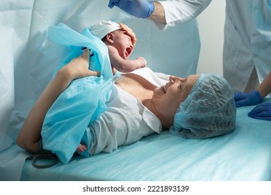 Mother holds newborn baby in hospital - Shutterstock ID 2221893139