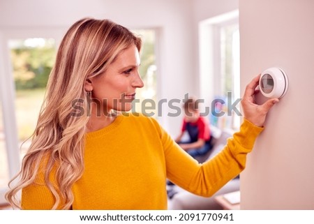 Mother At Home With Son Adjusting Smart Central Heating Thermostat Control Foto stock © 