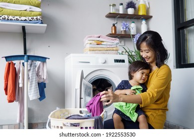 Mother A Housewife With A Baby Engaged In Laundry With Washing Machine