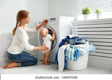 Mother A Housewife With A Baby Engaged In Laundry Fold Clothes Into The Washing Machine
