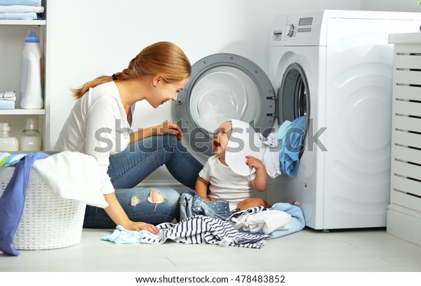 洗濯物を洗濯機に入れるために赤ちゃんと一緒に主婦をして洗濯をする の写真素材 今すぐ編集