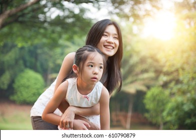 Mother Hugging Daughter In The Park , Asian Family Outdoor Lifestyle, Morning With Sun Flare.