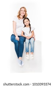 Mother Hugging Daughter While Sitting On White Cube Together Isolated On White