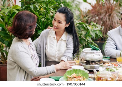 Mother Hugging Her Adult Daughter When They Are Sitting At Dinner Table At Family Celebration