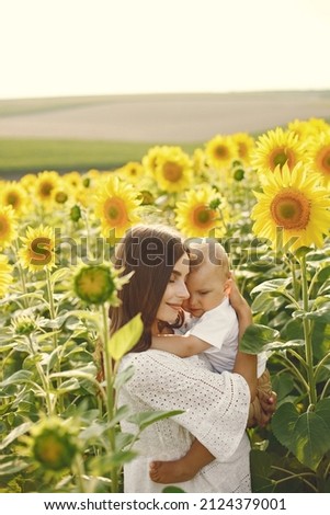 Mother hugging her son while standing in the sunflowers field