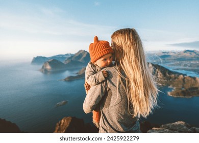 Mother hugging infant baby walking outdoor family lifestyle traveling in Norway summer vacations woman with child in mountains of Lofoten islands aerial view - Powered by Shutterstock