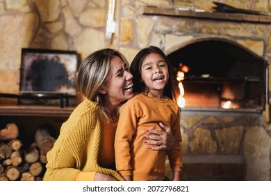 Mother hugging little daughter near fireplace at home during winter time - Mother and child love - Powered by Shutterstock