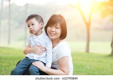 Mother Hugging Son In The Park, Asian Family Outdoor Lifestyle, Morning With Sun Flare.