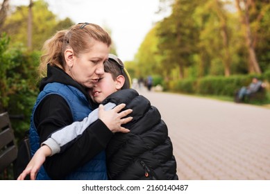 A mother hugs her little son, soothes him, caress his back, the boy fell in the park while playing and needs help from his mother. A tired boy is resting on mother's lap - Shutterstock ID 2160140487