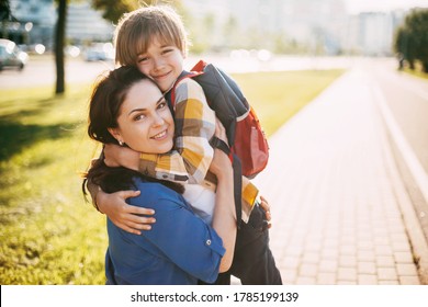 A Mother Hugs Her Young Son On The Way To School, And A Mother And Boy Say Goodbye Before School. Concept Of Education And Training