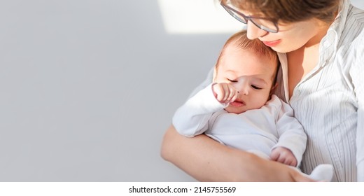 Mother Hugs Little Baby In White Onesie. Mom And 3-month Old Son Or Daughter. Family Life. Horizontal Banner With Copy Space. 