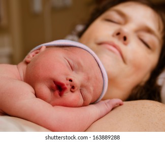 Mother And Infant Child Resting After Delivery At Hospital