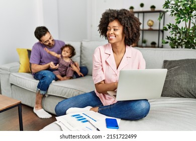 Mother Of Interracial Family Working Using Computer Laptop At Home Looking Away To Side With Smile On Face, Natural Expression. Laughing Confident. 