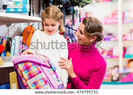 Mother and kid becoming a student buying school satchel or bag in store