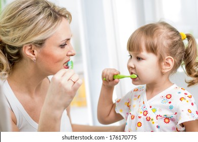 Mother And Kid Brushing Teeth In Bathroom