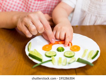 Mother And Kid Girl Making Funny Face From Vegetables On Plate