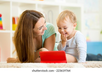 Mother And Kid Play At Tablet Computer At Nursery