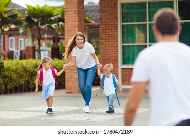 Mother And Kids After School. Young Mom Picking Up Children After Lessons In Kindergarten Or Preschool. Pick Up Students. Boy And Girl Running To Parents In School Yard.