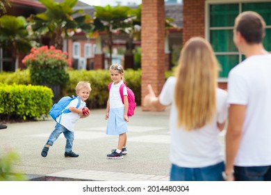 Mother And Kids After School. Young Mom Picking Up Children After Lessons In Kindergarten Or Preschool. Pick Up Students. Boy And Girl Running To Parents In School Yard.